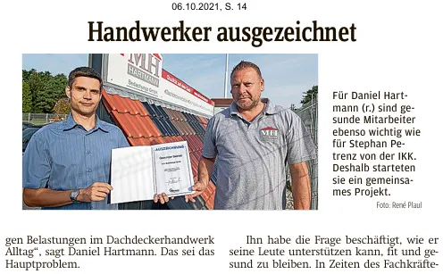 Zwei Männer halten Auszeichnungen vor einem Dachdeckerfahrzeug, Titel "Handwerker ausgezeichnet".
