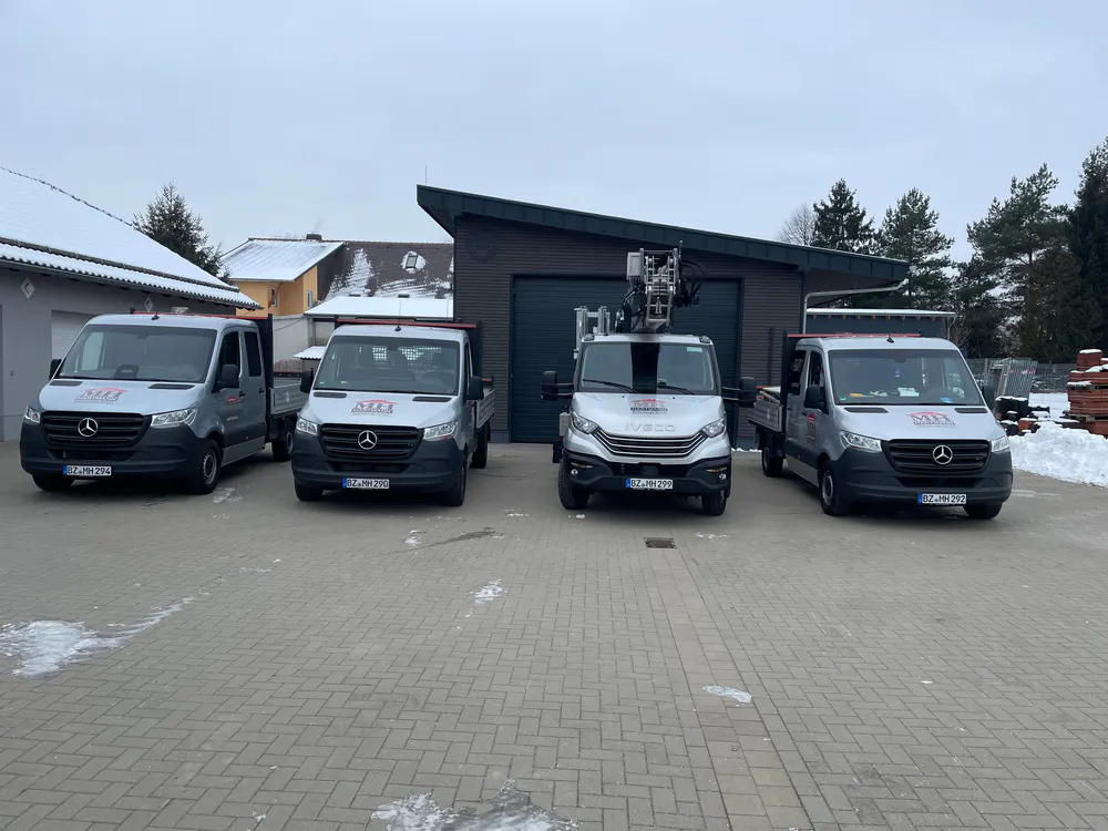Vier graue Lieferwagen mit "AREZ" Logo, davon einer mit Arbeitsbühne, stehen auf einem gepflasterten Hof im Schnee.