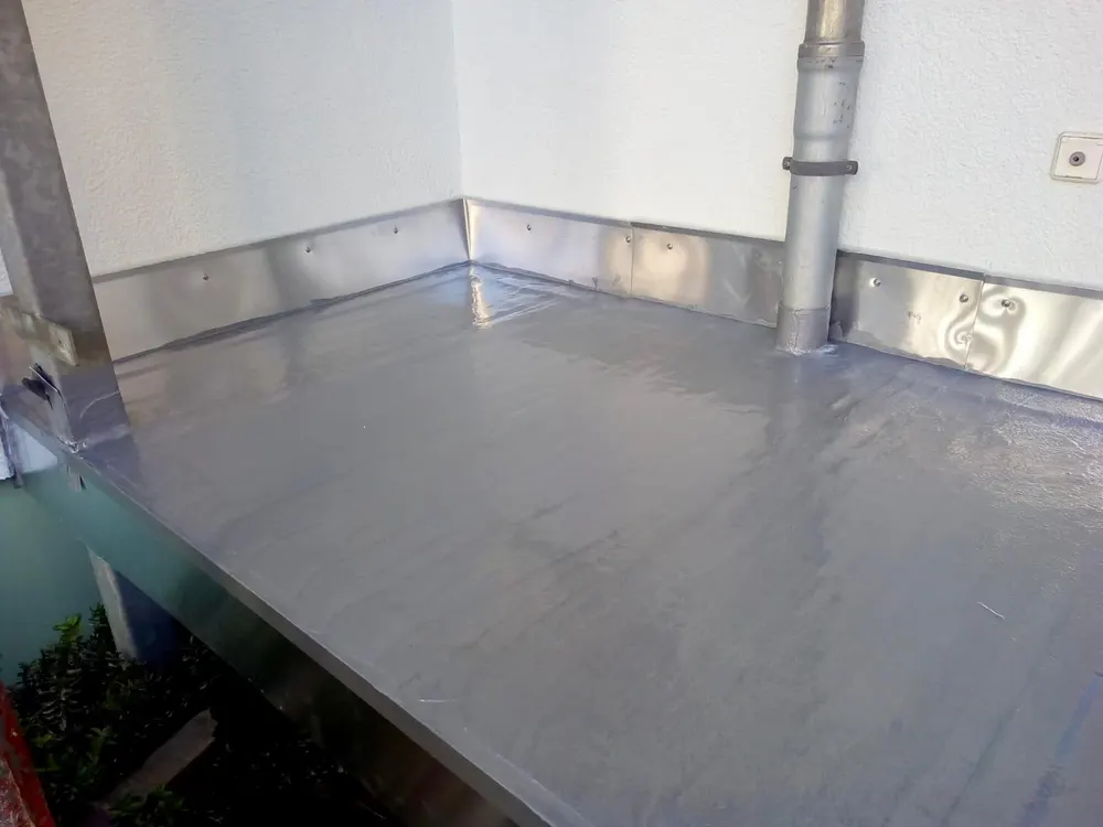 Grauer, glänzender Boden mit silbernen Blechverkleidungen an den Wänden und einem Abflussrohr in der Ecke.